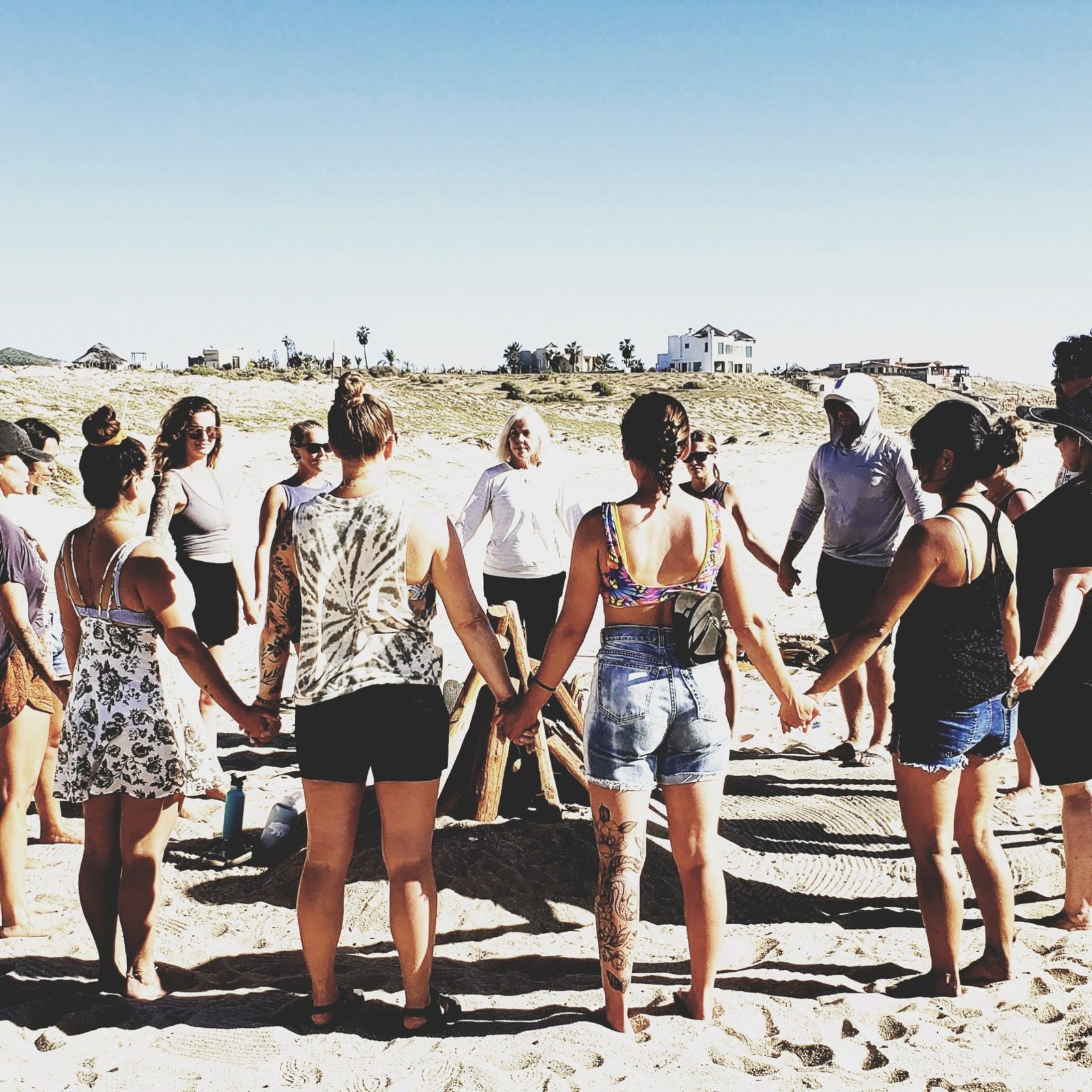 A group holding hands in a circle on a beach