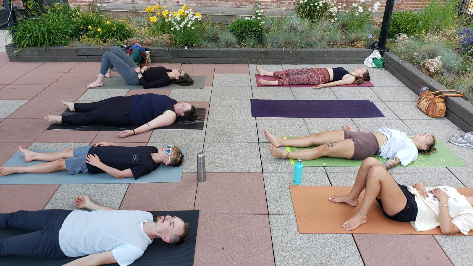 Participants resting on yoga mats in an outdoor garden space